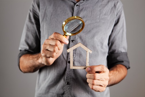 Man holding magnifying glass inspecting home